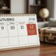 Calendário de outubro de 2026 com os dias 10, 11 e 12 destacados e uma mala de viagem ao lado.
