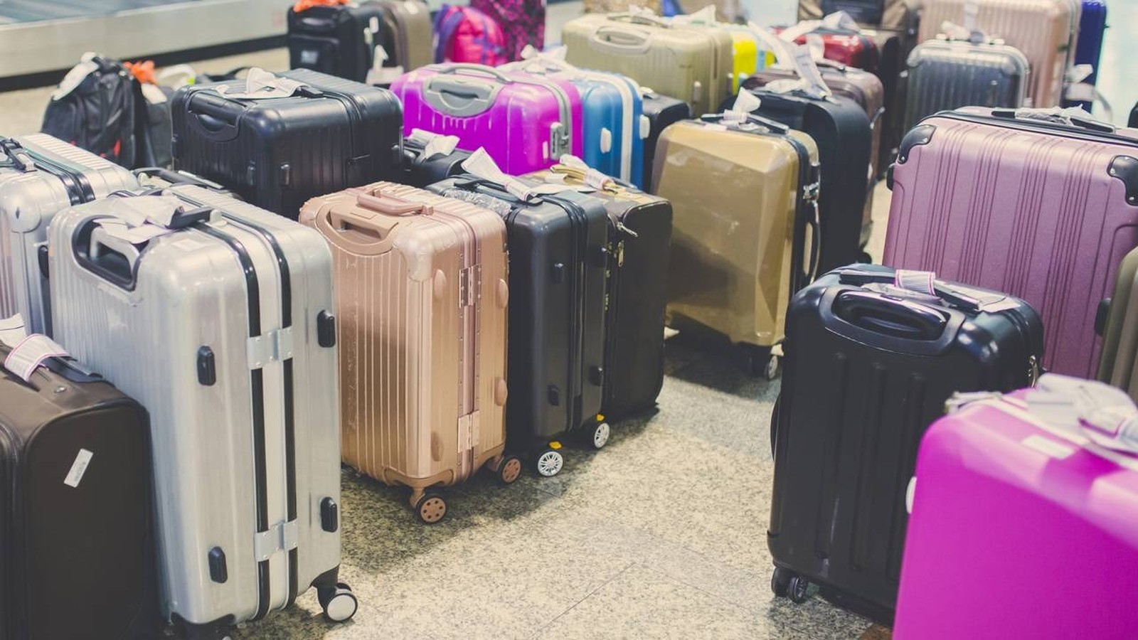 Várias malas de viagem coloridas e de diferentes tamanhos agrupadas em um piso de azulejos