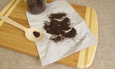 Pó de café espalhado em papel amassado e em uma colher de madeira sobre uma tábua