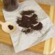 Pó de café espalhado em papel amassado e em uma colher de madeira sobre uma tábua
