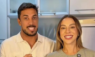 Casal sorridente, homem e mulher, olhando para frente em ambiente interno claro
