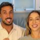 Casal sorridente, homem e mulher, olhando para frente em ambiente interno claro