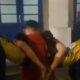 Dois agentes da Força Municipal escoltam homem algemado em camisa vermelha