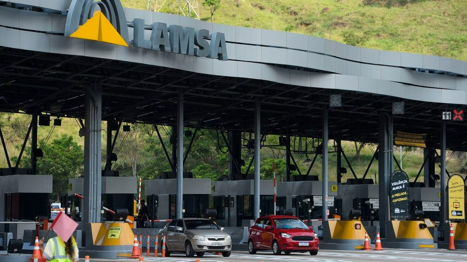 Praça de pedágio da Linha Amarela com sinalização LAMSA, dois carros e funcionário