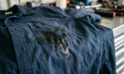 Camisa de trabalho azul com grande mancha de óleo preta e brilhante na área do bolso