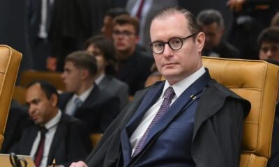 Ministro Cristiano Zanin, de óculos e toga, sentado em cadeira de couro