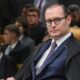Ministro Cristiano Zanin, de óculos e toga, sentado em cadeira de couro