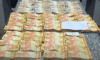 Grandes pilhas de notas de 20 reais brasileiras, presas com elásticos, sobre uma mesa