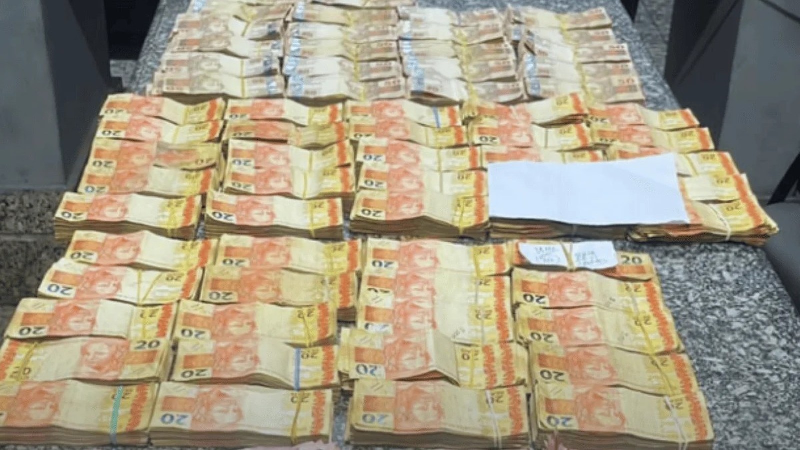 Grandes pilhas de notas de 20 reais brasileiras, presas com elásticos, sobre uma mesa