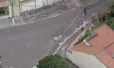 Rua de paralelepípedos e telhados vista de cima, com muitos papéis espalhados