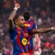Jogador Raphinha, do Barcelona, celebra no campo com os braços levantados em um estádio