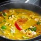 Moqueca de camarão com pimentões coloridos e coentro em panela de barro, com vapor visível