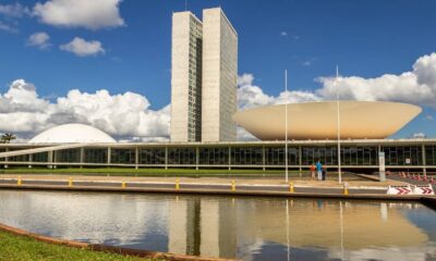 Congresso Nacional do Brasil com torres gêmeas, cúpula, bacia invertida, lago e céu azul