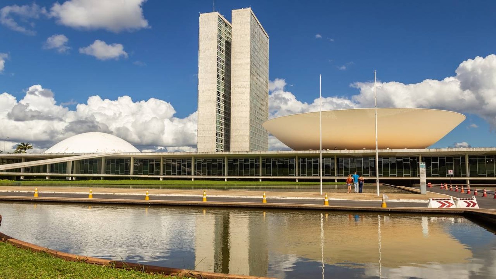 Congresso Nacional do Brasil com torres gêmeas, cúpula, bacia invertida, lago e céu azul
