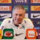 Carlo Ancelotti sorrindo em coletiva de imprensa com vários logotipos de patrocinadores