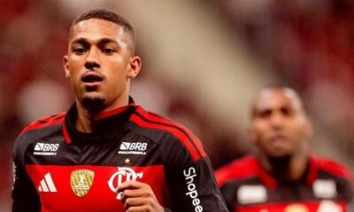 Homem em uniforme preto e vermelho do Flamengo com logos BRB e Shopee, outro jogador desfocado ao fundo.