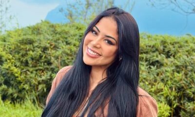 Gisele Nascimento sorri, cabelos escuros, em ambiente externo com folhagem verde