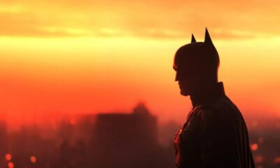 Batman em silhueta, perfil, contra um vibrante céu de pôr do sol laranja e vermelho