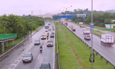 Wet highway traffic: cars, trucks (one 'NUTRYMAX'), motorcycles, and green roadside