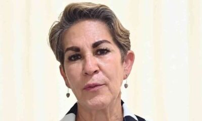 Retrato frontal de mulher madura com cabelo curto, brincos de coração e expressão neutra