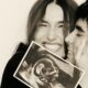 Mulher e homem sorridentes seguram ultrassom do bebê, foto em preto e branco