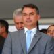 Flávio Bolsonaro de terno e gravata azul claro, cercado por outras pessoas em evento