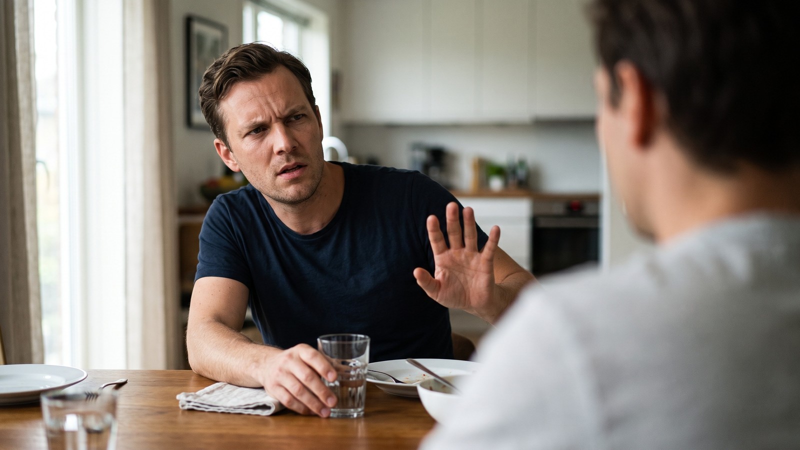 Homem com expressão séria e testa franzida faz gesto de "pare" com a mão para outro homem