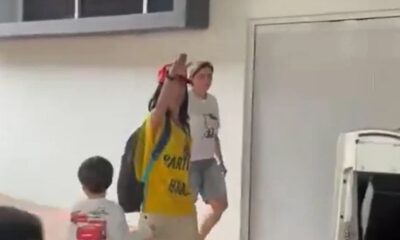 Mulher de camisa amarela, boné vermelho, faz saudação nazista perto de criança