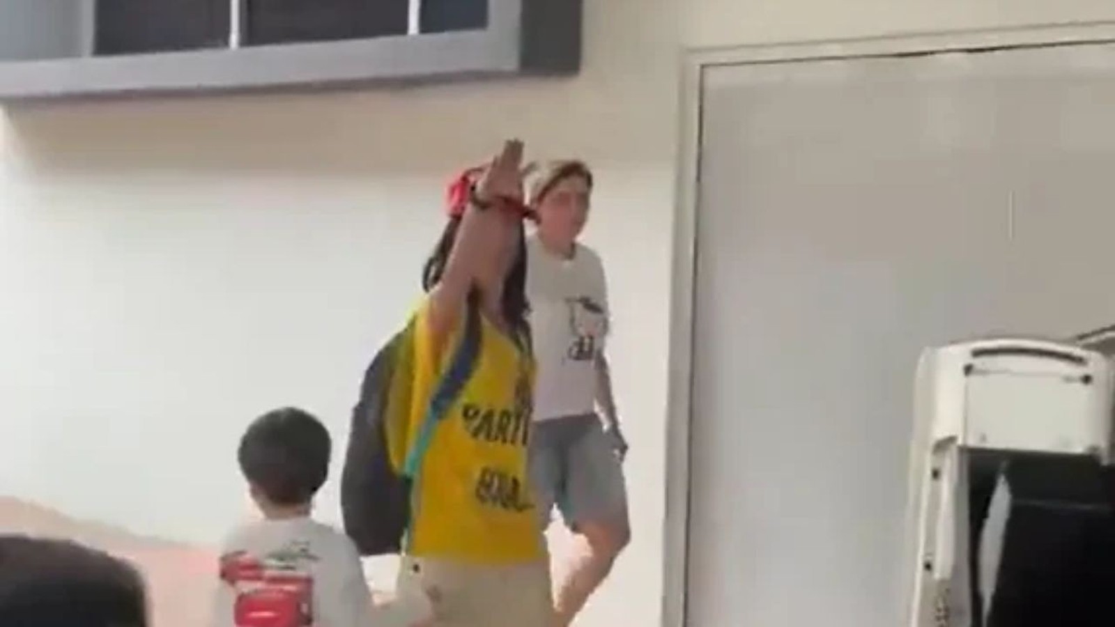 Mulher de camisa amarela, boné vermelho, faz saudação nazista perto de criança