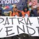 Grupo de manifestantes segura banner branco com "LA PATRIA NO SE VENDE!!!" e "autonoma" ao fundo