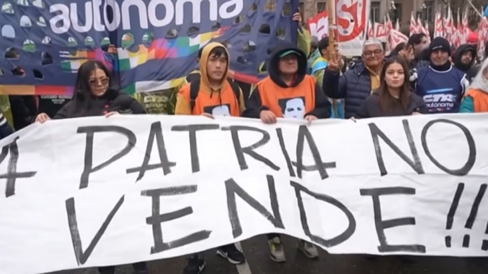 Grupo de manifestantes segura banner branco com "LA PATRIA NO SE VENDE!!!" e "autonoma" ao fundo