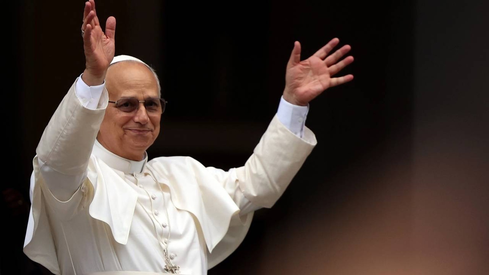 Papa Leão XIV, em vestes brancas, sorri e acena com ambas as mãos