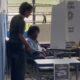 Mulher idosa em cadeira de rodas vota em urna eletrônica, com auxílio