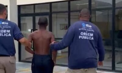 Dois agentes da Ordem Pública escoltam jovem sem camisa. Logos 'Rio Ordem Pública'