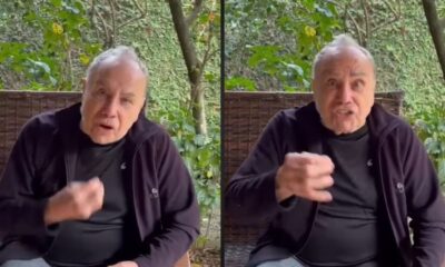 Homem idoso, Stenio Garcia, gesticula expressivamente em vídeo, usando blusa preta, fundo verde