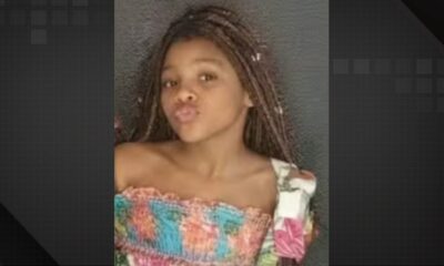Close-up de uma menina negra com tranças, lábios fazendo bico, vestindo uma blusa colorida