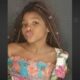 Close-up de uma menina negra com tranças, lábios fazendo bico, vestindo uma blusa colorida
