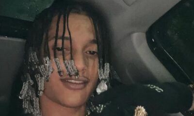 Oruam, homem jovem, dreadlocks com miçangas, sorri levemente dentro de um carro. Usa anéis