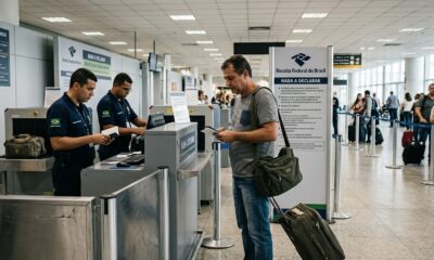Funcionários da Receita Federal e passageiro com bagagem em área de declaração de bens em aeroporto
