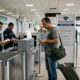 Funcionários da Receita Federal e passageiro com bagagem em área de declaração de bens em aeroporto