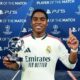 Jogador Endrick sorri segurando troféu de Melhor em Campo da Champions League em fundo azul