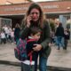 Mulher chorando ao telefone, abraçando menino com mochila em frente à escola "ESCOLA MUNICIPAL PRIMÁRIO"