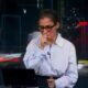 Jornalista Renata Vasconcellos com a mão na boca, tossindo em bancada de telejornal ao vivo.