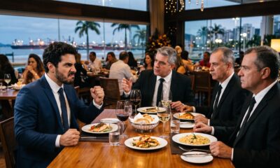 Quatro homens de terno em restaurante. Um deles com rosto zangado e punhos cerrados