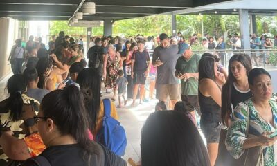 Multidão de pessoas aguarda em fila dentro de um corredor iluminado de um centro comercial
