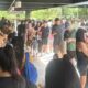 Multidão de pessoas aguarda em fila dentro de um corredor iluminado de um centro comercial