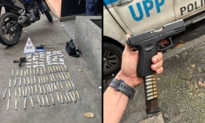 Pistola, rádio, cone da Polícia Militar e drogas embaladas no chão, e mão segurando pistola com carregador estendido