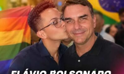 Pessoa jovem beija Flávio Bolsonaro na bochecha, com bandeira arco-íris e do Brasil