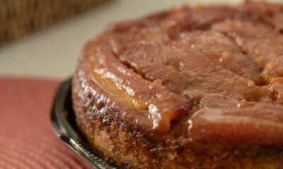 Close-up de bolo de banana caramelizado em prato, com superfície brilhante e detalhes da fruta