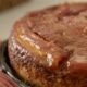 Close-up de bolo de banana caramelizado em prato, com superfície brilhante e detalhes da fruta